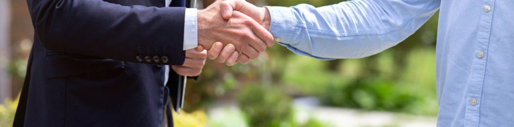 A property manager and rental property owner shake hands.